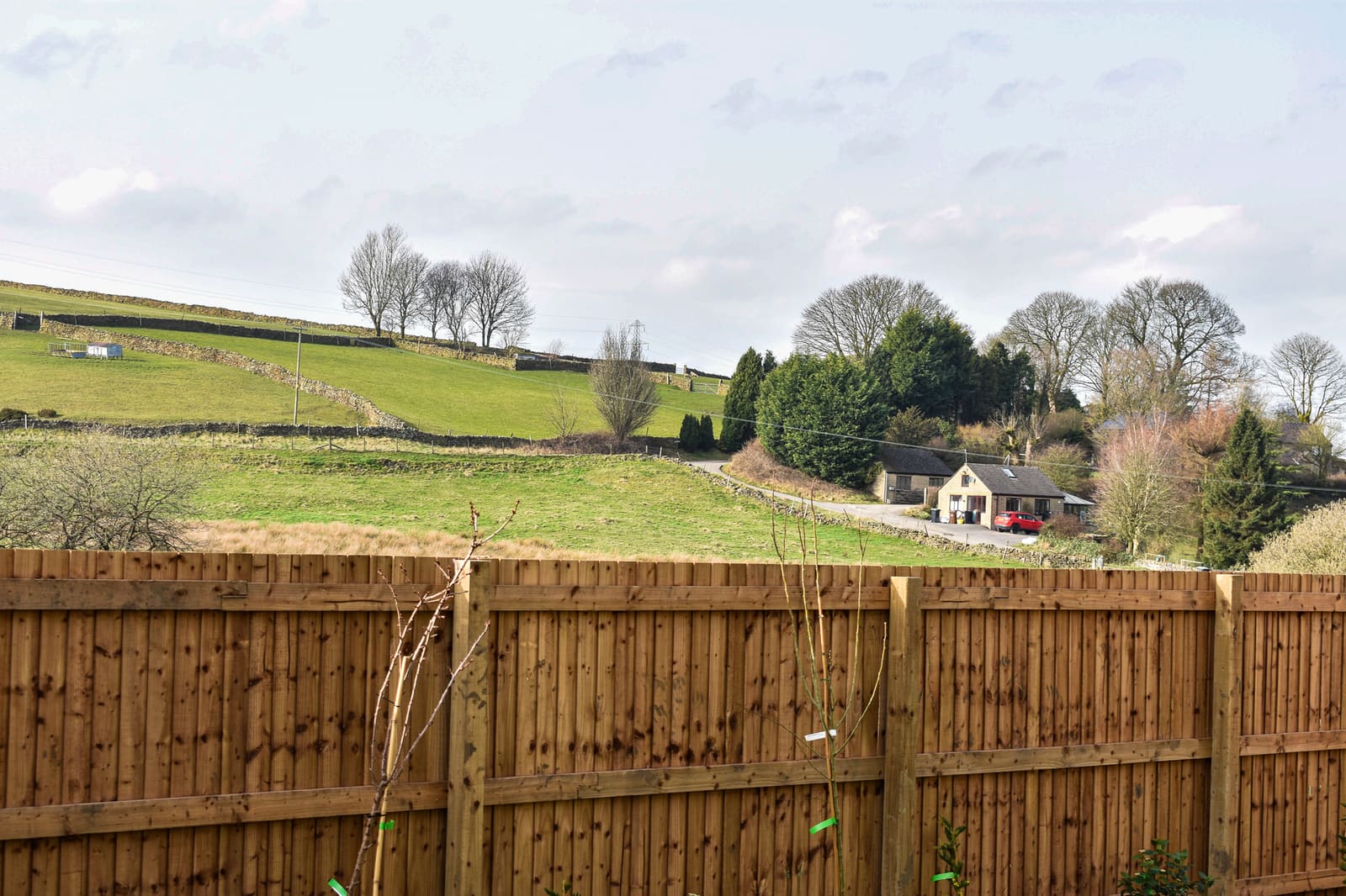 View across the fields towards a Peak District cottage, near Hallstead Meadow