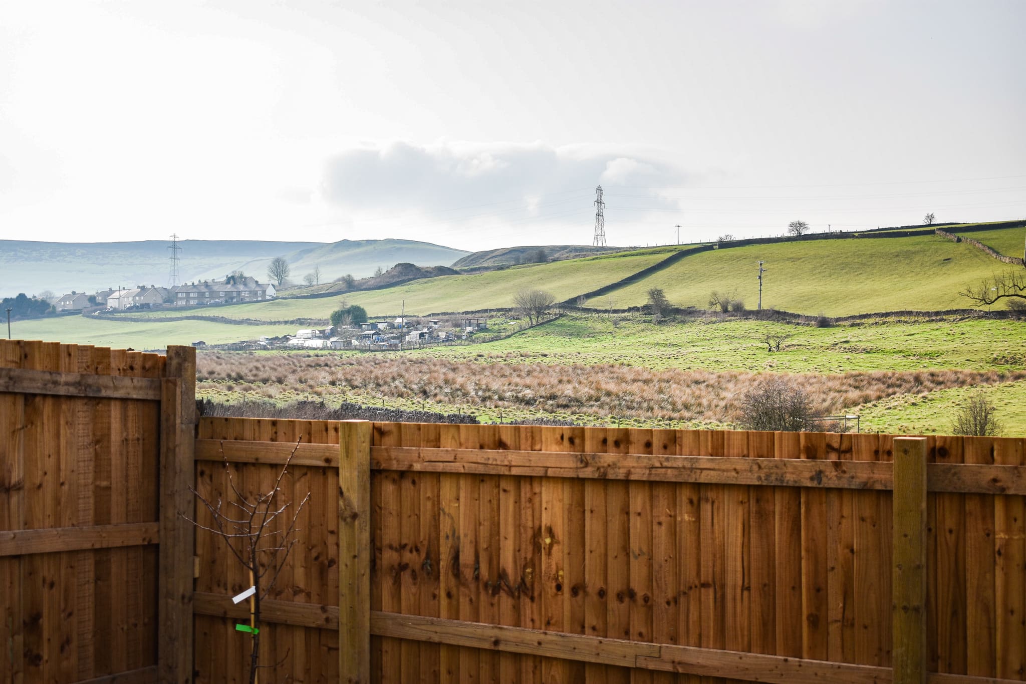 A drystone wall tracing the hillside beyond a Hallstead Meadow garden fence